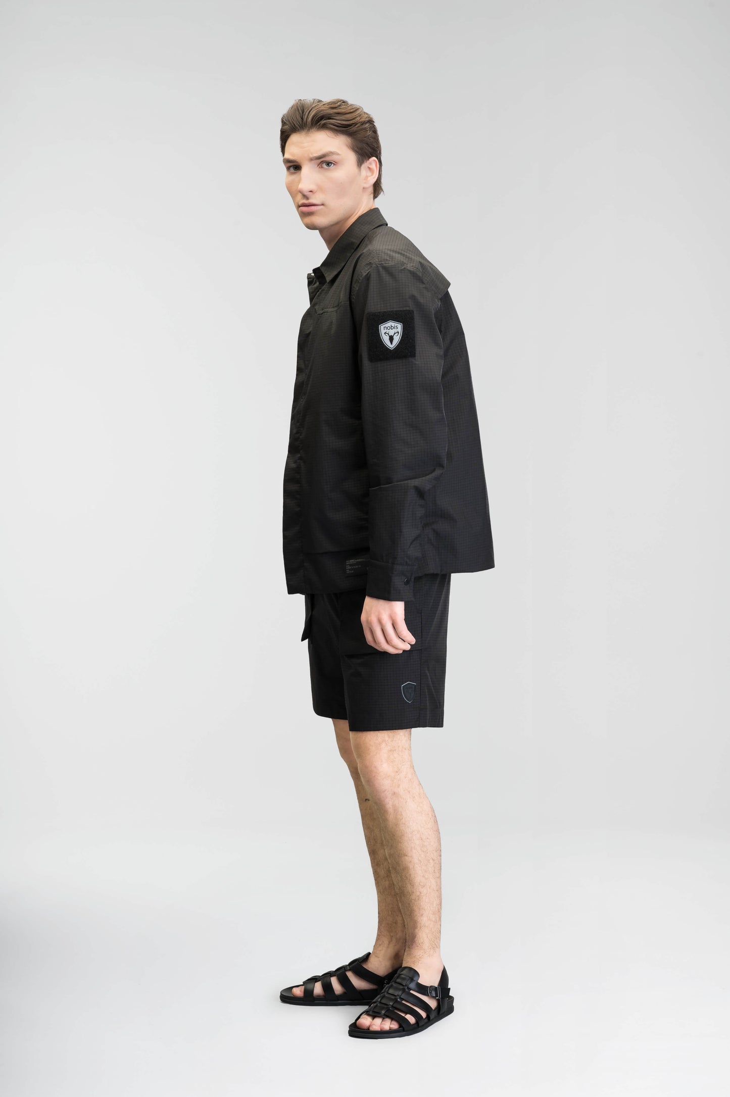 Farson Men's Waterproof Overshirt in Black made from premium recycled polyester ripstop with a DWR coating. Features a concealed snap-button front placket, adjustable snap cuffs, invisible chest zip pocket, dual zippered waist pockets, pit zip ventilation, and seam-sealed construction for enhanced weather protection. Designed in Canada.