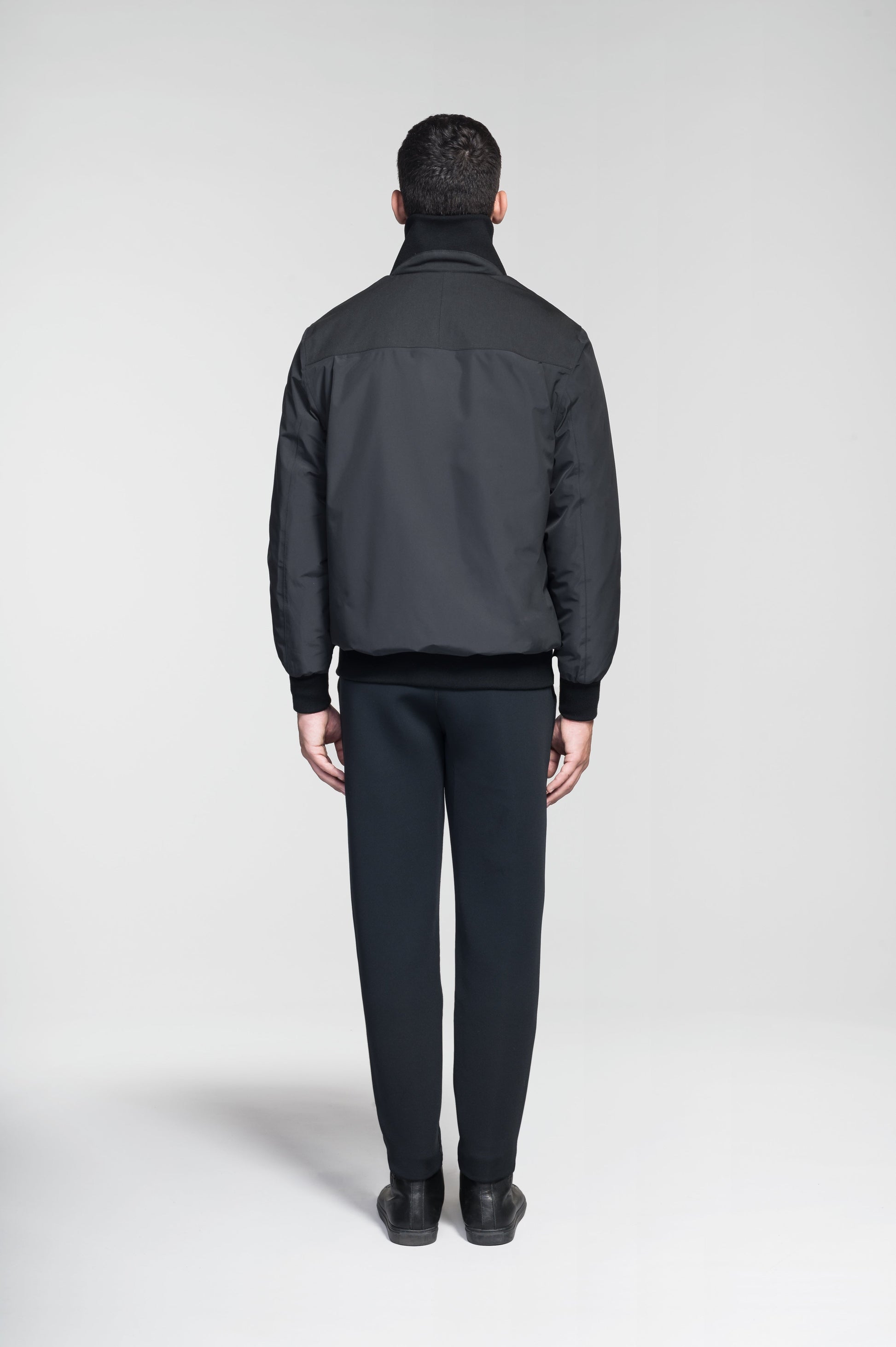 Flint Men's Tailored Rib Collar Jacket in hip length, premium 3-ply Micro Denier fabrication, premium 4-way stretch, water resistant Primaloft Gold Insulation Active +, flap pockets with magnetic closure at waist, side entry pockets at waist, ribbed sleeve cuffs, two-way branded zipper at centre front, box pleat detailing at centre back, large interior zipper pocket, and interior button pocket at left chest, in Black