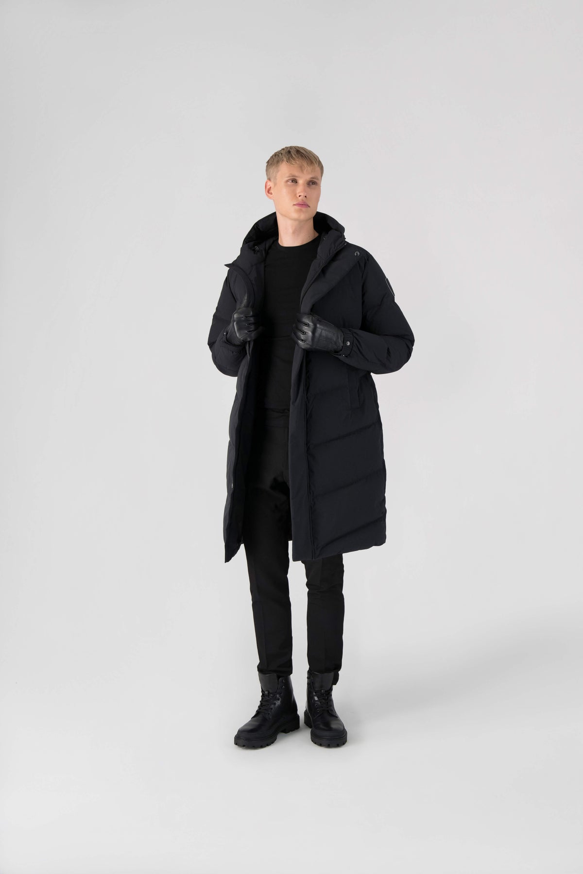 Granger long jacket in Black stretch ripstop fabric with DWR coating, insulated with Canadian white duck down and Primaloft. Features a two-way zipper, magnetic closure, and adjustable cuffs for warmth and weather protection.
