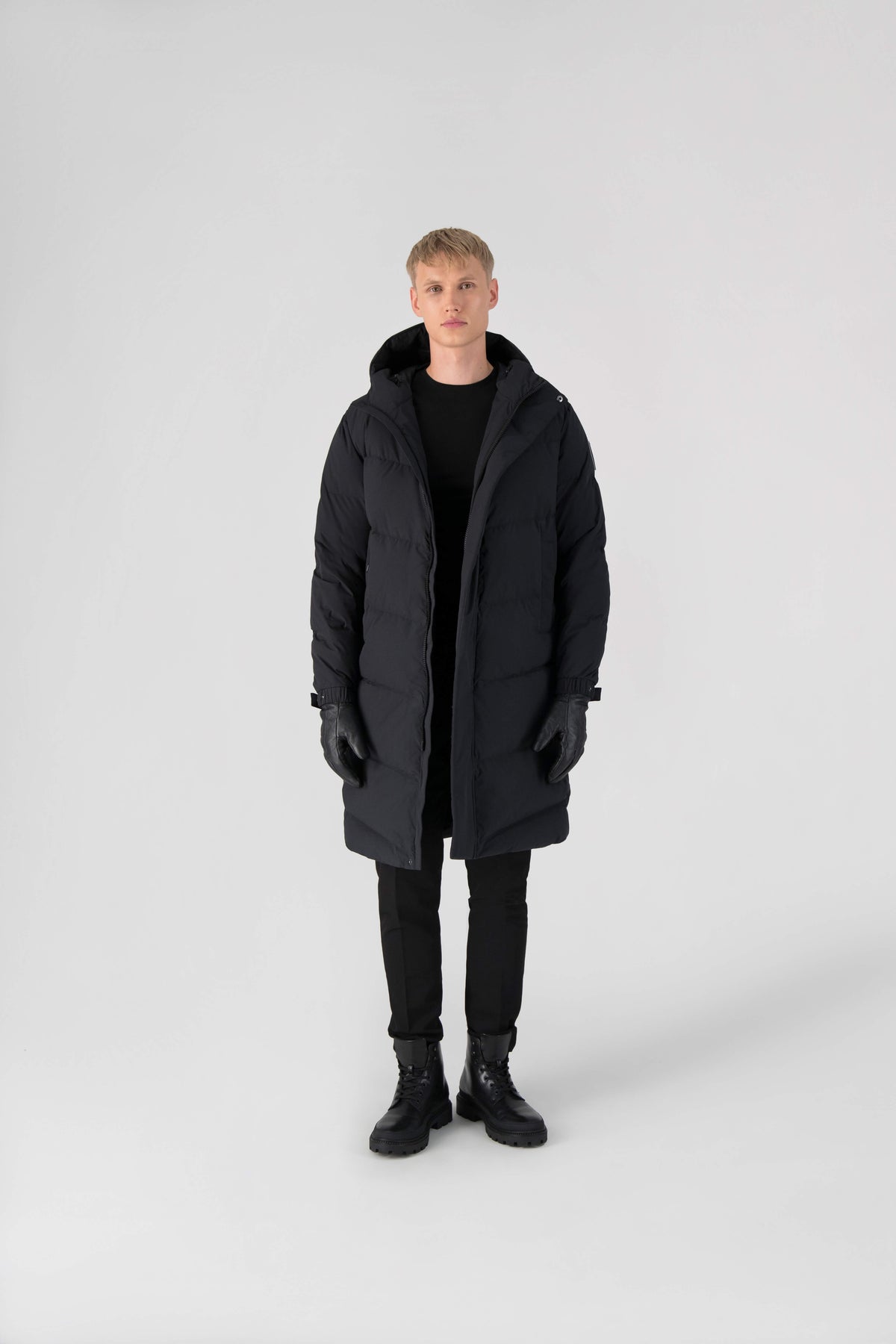 Granger long jacket in Black stretch ripstop fabric with DWR coating, insulated with Canadian white duck down and Primaloft. Features a two-way zipper, magnetic closure, and adjustable cuffs for warmth and weather protection.