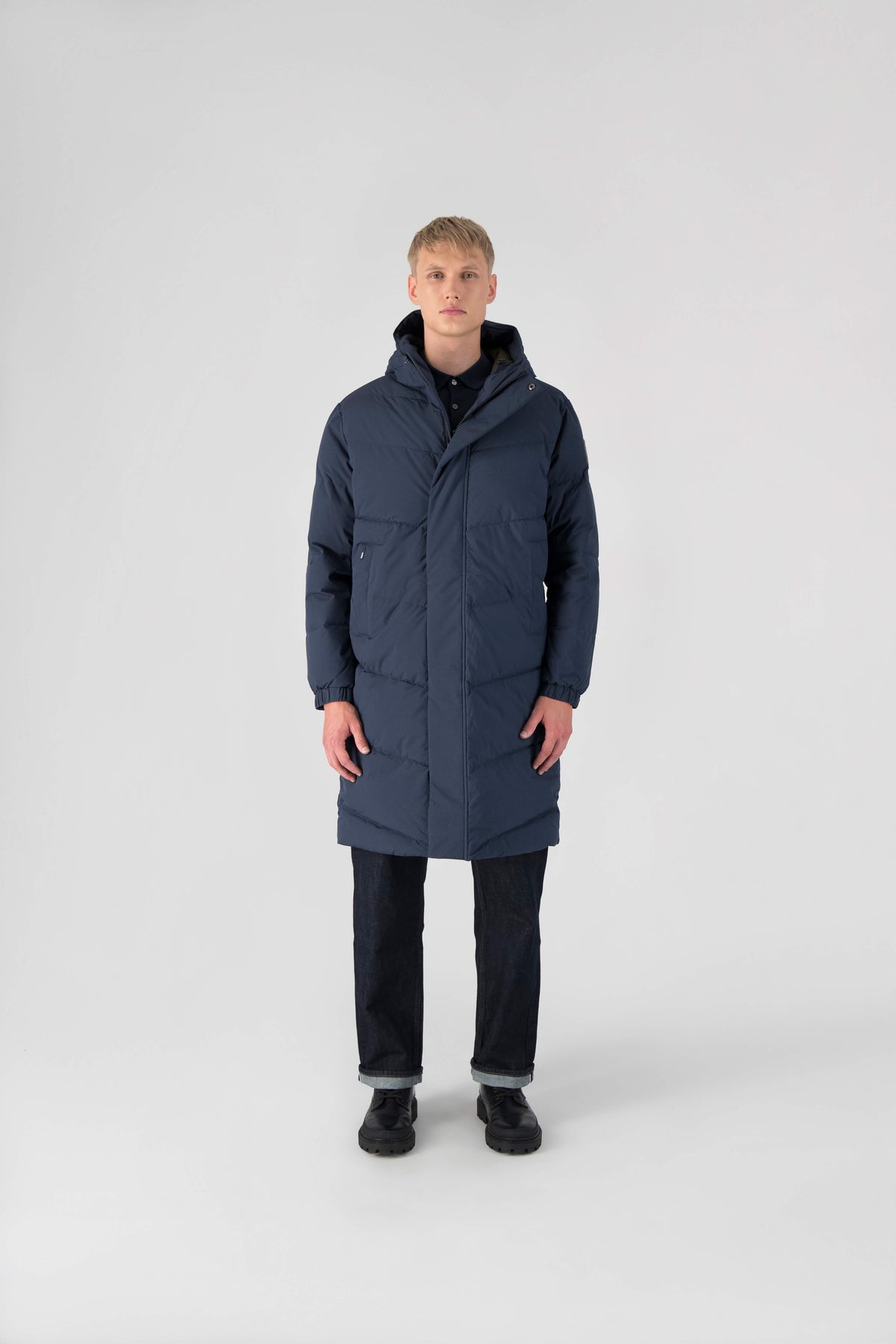 Granger long jacket in Marine stretch ripstop fabric with DWR coating, insulated with Canadian white duck down and Primaloft. Features a two-way zipper, magnetic closure, and adjustable cuffs for warmth and weather protection.