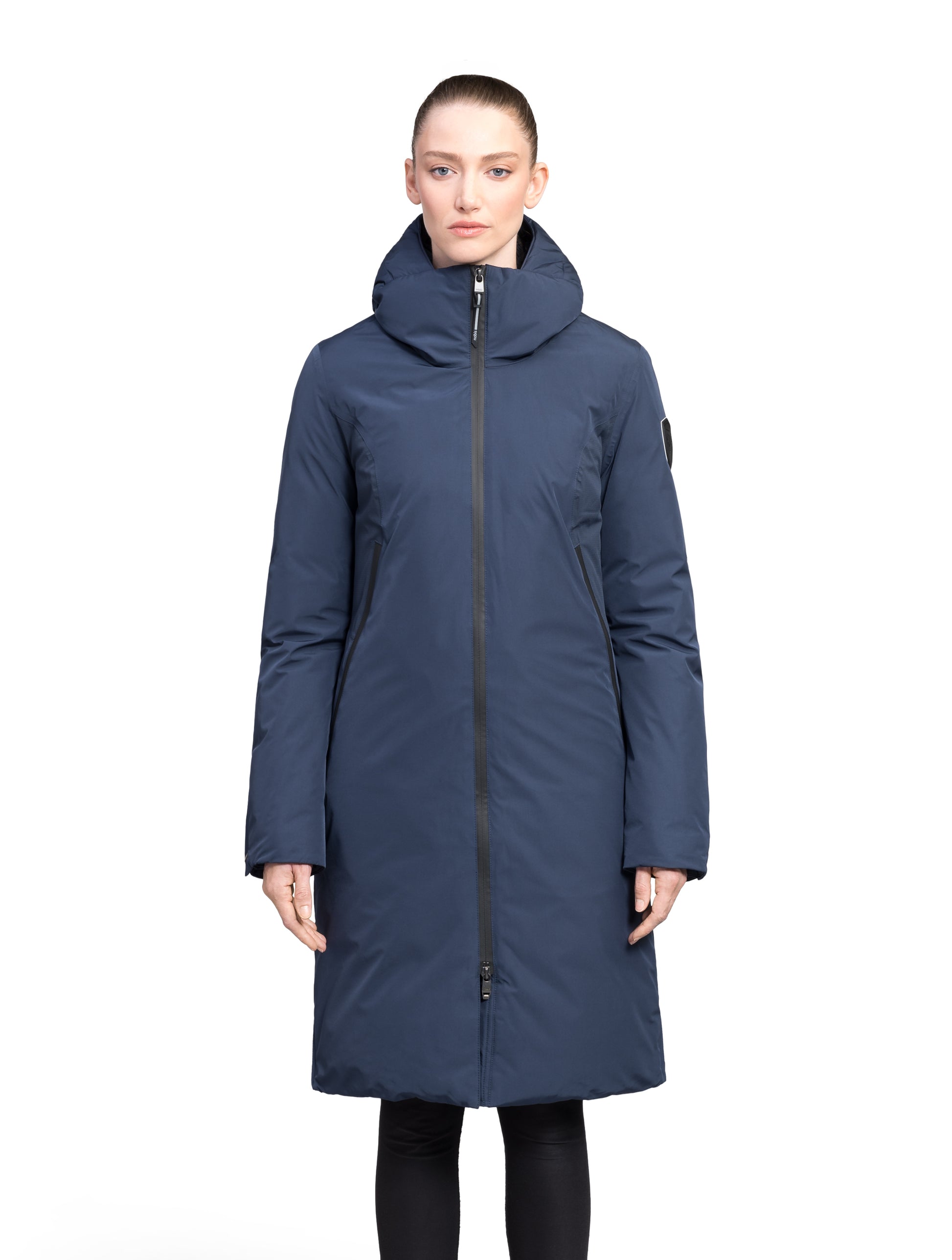 Inara Women's Performance Parka in knee length, premium 3-ply micro denier and stretch ripstop fabrication with DWR coating, Premium Canadian White Duck Down insulation, non-removable down-filled hood, centre front two-way zipper, large vertical zipper pockets along waist, zipper vents along bottom side hem, in Marine