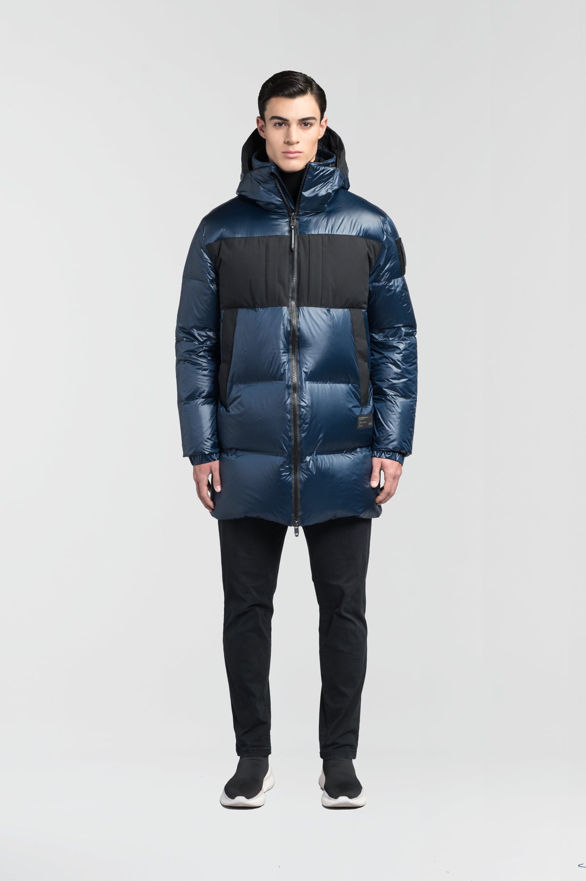 Neelix Men's Long Puffer Jacket in thigh length, premium cire technical nylon taffeta and stretch ripstop fabrication, Premium Canadian origin White Duck Down insulation, non-removable down-filled hood, two-way centre-front zipper, pit zipper vents, hidden chest zipper pockets, fleece-lined magnetic closure waist pockets, in Marine