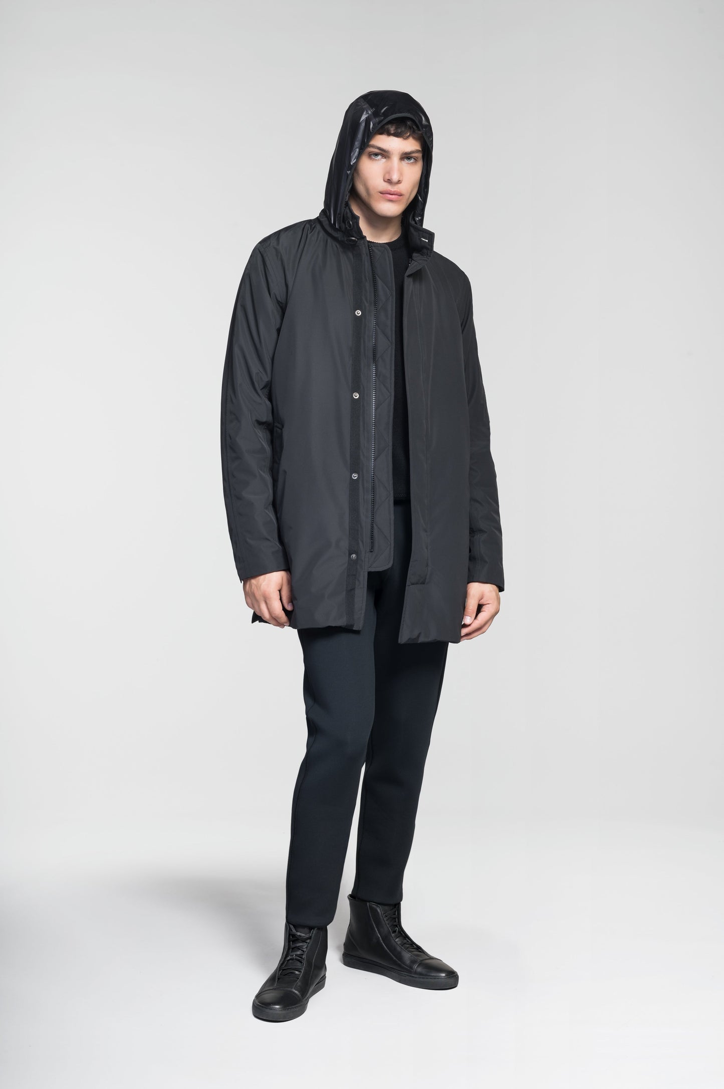 Pike Men's Tailored Mac Coat in thigh length, premium 3-ply Micro Denier fabrication at body and cire technical nylon taffeta fabrication at hood, premium 4-way stretch, water resistant Primaloft Gold Insulation Active+, hidden 2-way zipper with snap closure wind flap, single welt pockets with magnetic closure at waist, hidden snap placket at cuffs, pit zippers for ventilation, interior zipper pocket at right chest, and interior button pocket at left chest, in Black