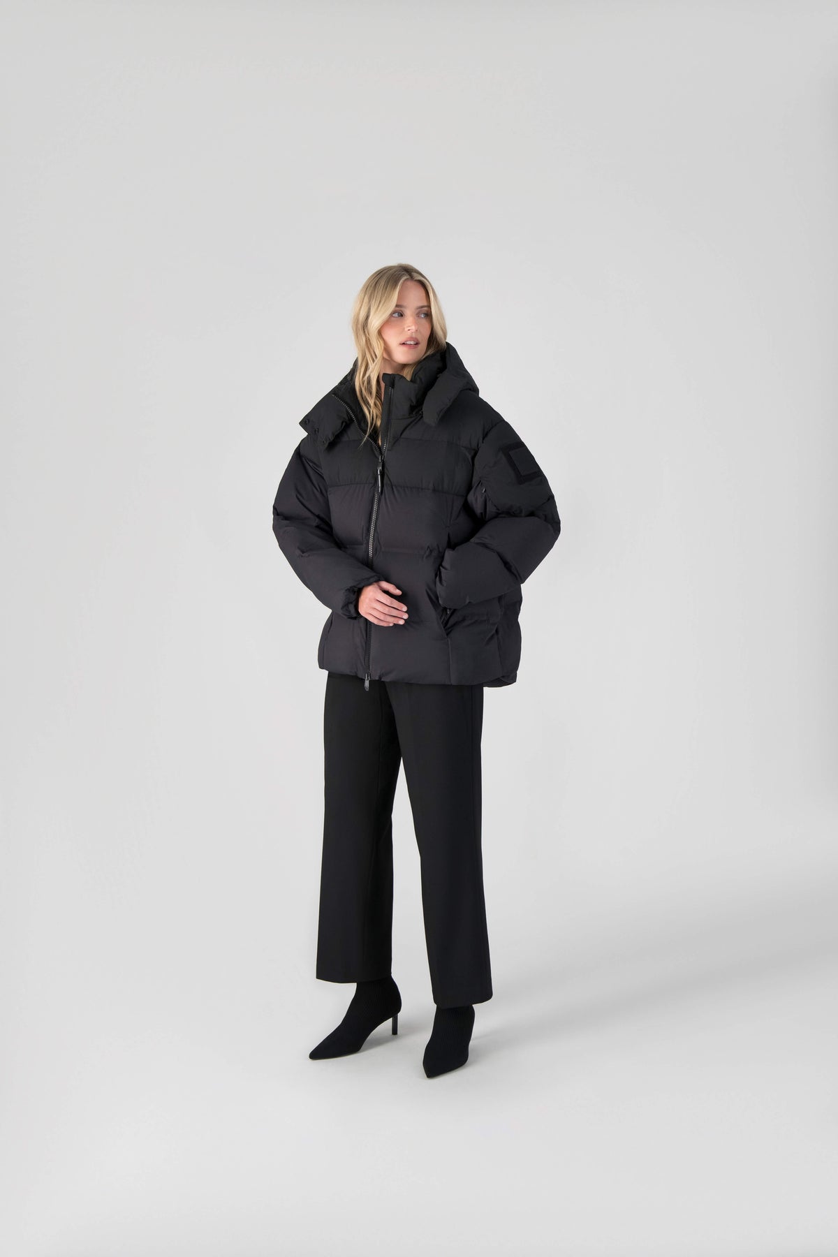 Una Ladies Performance Puffer in hip length, Technical Taffeta and Durable Stretch Ripstop fabrication, Premium Canadian White Duck Down insulation, removable down filled hood, centre front two-way zipper, and side-entry pockets at waist, in Black