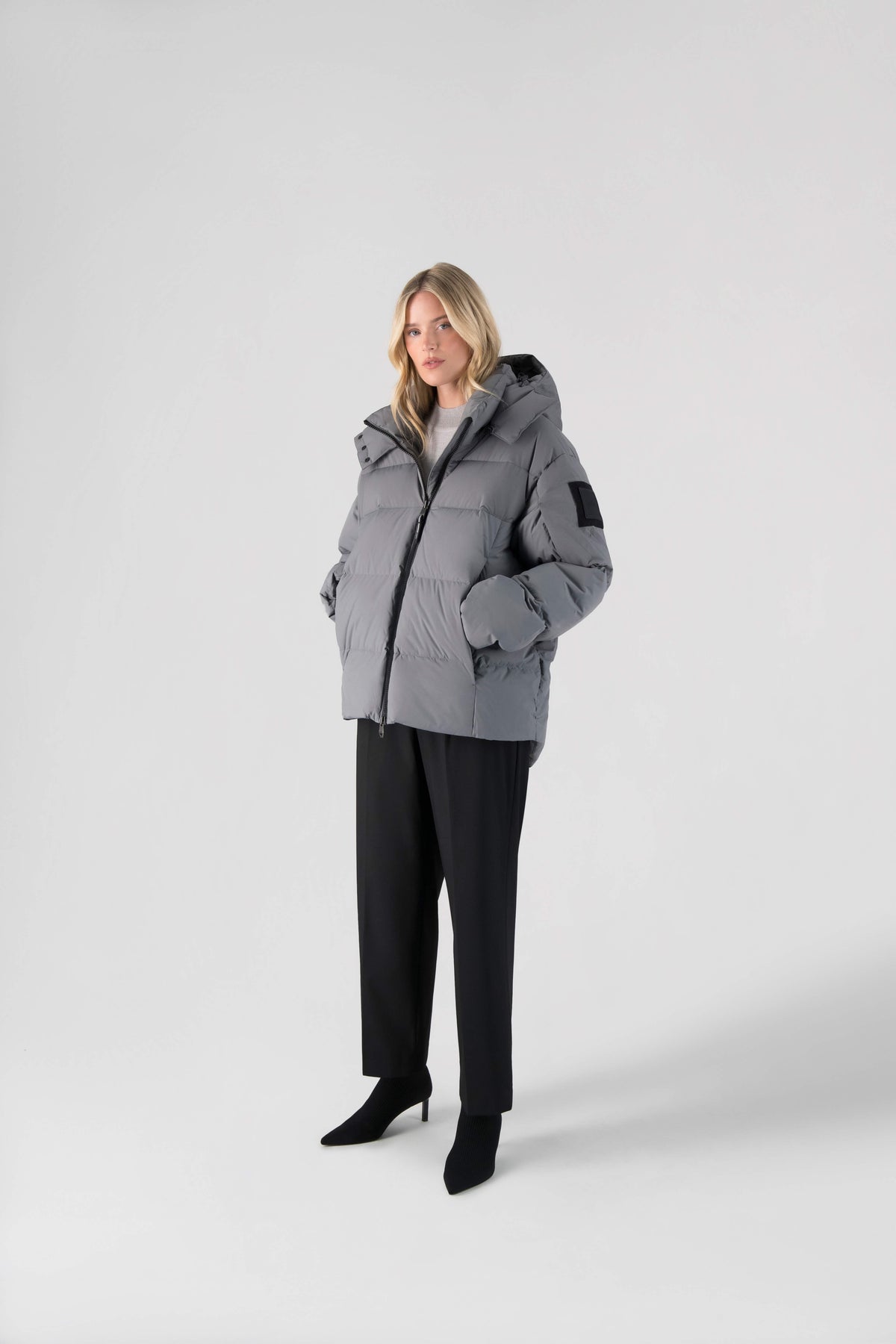 Una Ladies Performance Puffer in hip length, Technical Taffeta and Durable Stretch Ripstop fabrication, Premium Canadian White Duck Down insulation, removable down filled hood, centre front two-way zipper, and side-entry pockets at waist, in Concrete