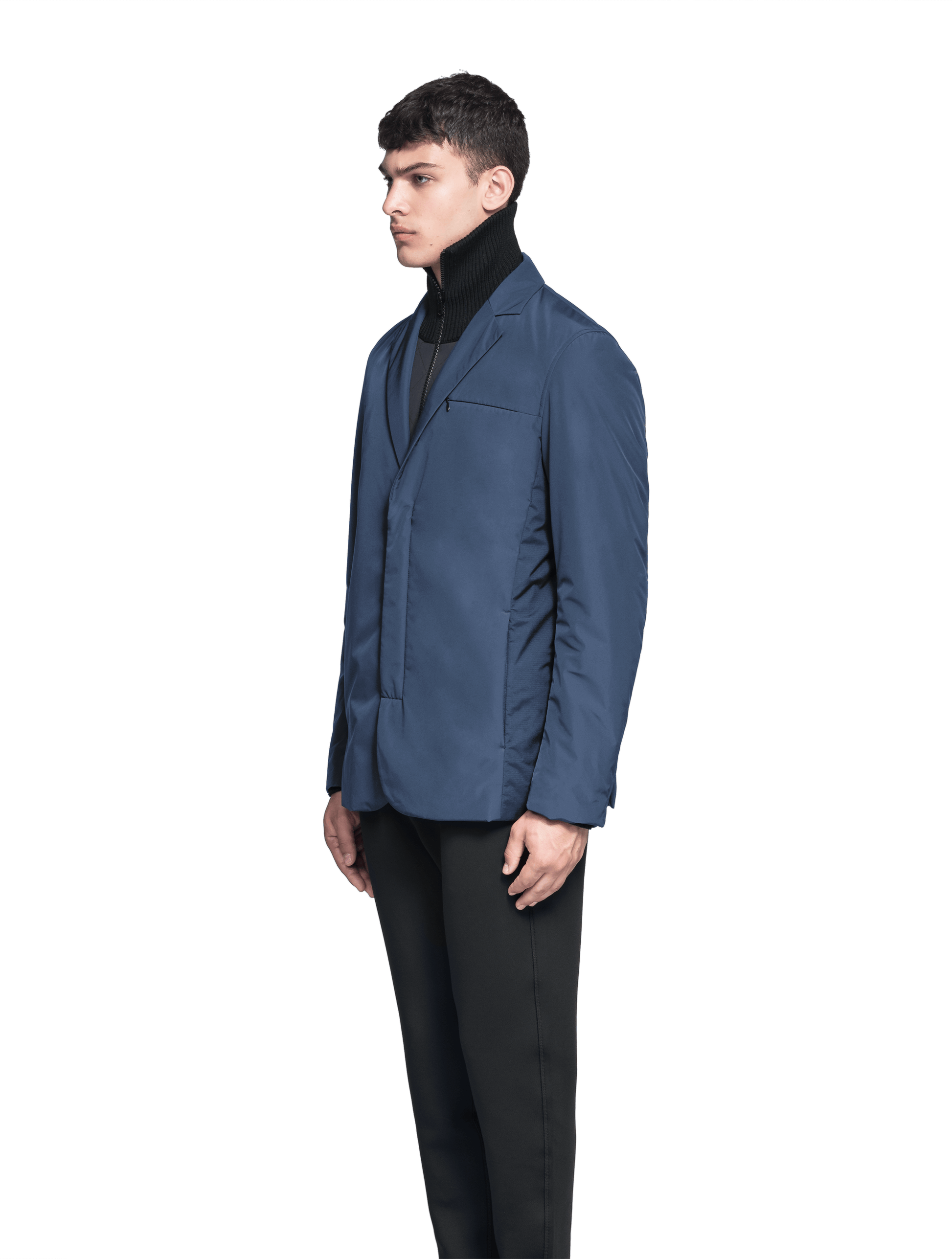 Cody Men's Tailored Travel Blazer in 3-ply micro denier and stretch nylon fabrication with DWR coating, Primaloft Gold Insulation Active+, hidden two-way zipper at centre front with snap closure placket, three invisible exterior zipper pockets, double back pleats, and hidden snap placket at cuffs, in Marine